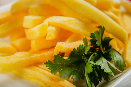 Fresh fried potatoes on a white plate with tomato sauce.