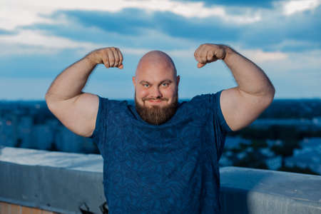 Big bearded bodybuilder on the rooftop in the evening.の写真素材