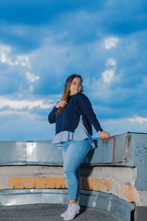 Beautiful young woman on the rooftop in the evening.の写真素材