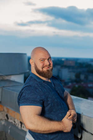 Big bearded bodybuilder on the rooftop in the evening.の写真素材