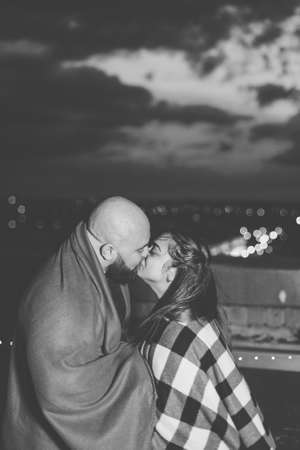 Beautiful couple on the roof under a blanket in the evening.の写真素材
