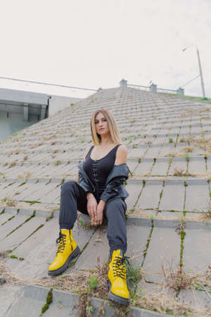Beautiful woman sits on concrete structures in cloudy weather.