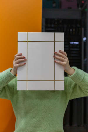 Young woman with kitchen facade sample in hands.
