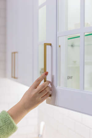 Young woman with in the kitchen holding the cabinet handle.の写真素材