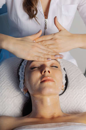 Professional beautician woman massaging face to client.の写真素材