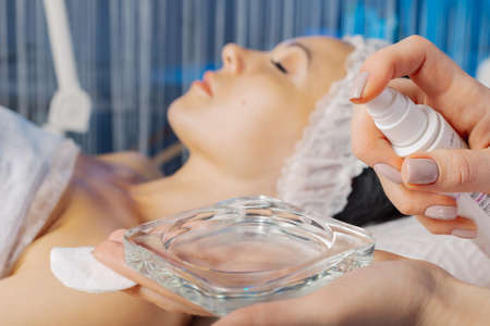 A professional beautician treats the container for the cream with an antiseptic.の写真素材