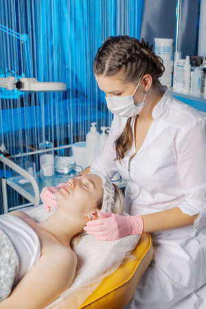 Professional beautician makes a facial massage to a woman.の写真素材