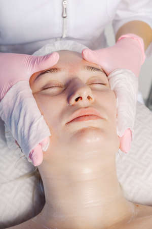Professional beautician woman washes the clients face with napkins.の写真素材