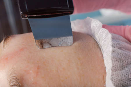 A professional cosmetologist performs an ultrasonic face cleaning procedure for a woman.の写真素材