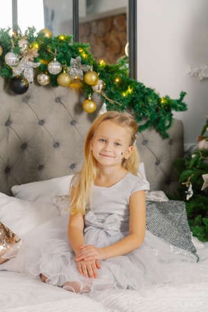 Beautiful little girl sitting on the New Years bed.の写真素材