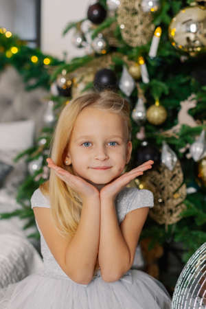 Beautiful little girl sitting by the Christmas tree.の写真素材