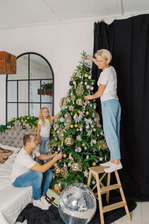Beautiful young happy family decorate the christmas tree.の写真素材
