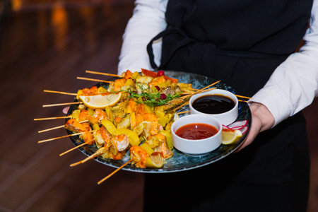 Shish kebab from seafood and red fish on wooden skewers on a plate with sauces.の写真素材