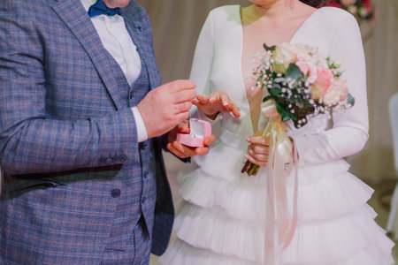 Newlyweds exchange rings, groom puts the ring on the brides hand in marriage registry officeの写真素材
