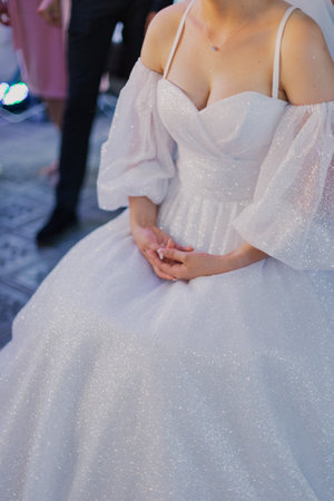 Beautiful tender hands of a bride who sits in a wedding dress on her wedding dayの写真素材