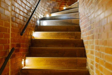 A beautiful wooden staircase with illuminated brick trim goes up. bright yellow lights. new staircase designの写真素材
