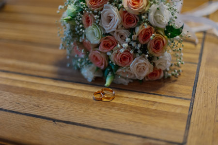 A wedding bouquet of handmade fresh flowers lies on a wooden table on which wedding rings lie on this happy day. wedding detailsの写真素材