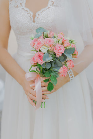 Beautiful young bride holding a wedding bouquet of natural flowers on her wedding day. Happy bride .front viewの写真素材