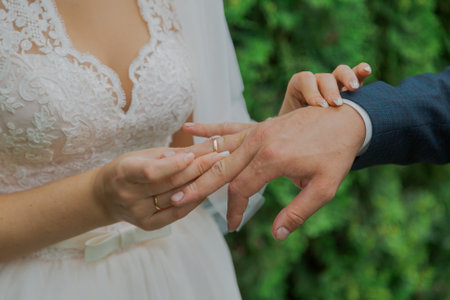 A beautiful young bride puts a wedding ring on her finger to the groom on her wedding day, they are happyの写真素材