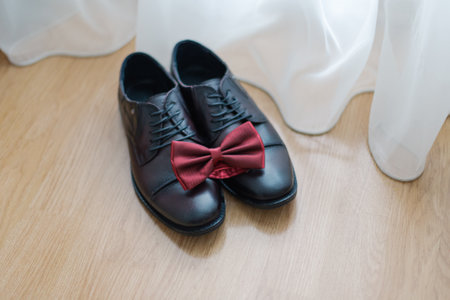 The grooms black shoes stand near the curtains on the floor wedding dayの写真素材