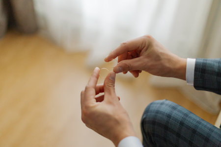 A young groom on his wedding day holds wedding gold rings in his hands he is very happyの写真素材