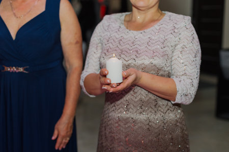 The parents of the newlyweds hold a burning candle in their hands to light the family hearth at the wedding ceremony.の写真素材