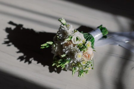 A beautiful wedding bouquet of fresh flowers lies on the floor lit by the sun and casts a shadowの写真素材
