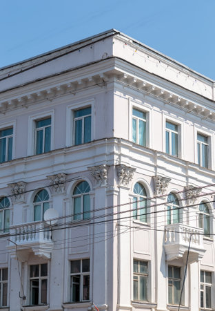 The angle of the facade of the old building that was built 100 years ago against the backdrop of the blue sky. Ancient decoration of the building. Restoration of buildings. The wires on the frontの写真素材