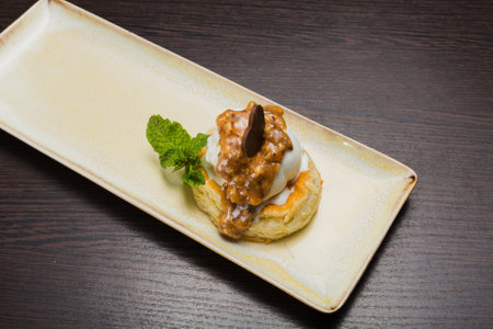 Dessert with puff pastry and ice cream drizzled with caramel on a plateの写真素材