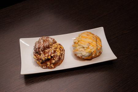 Two sweet pastries on a white plate and on a wooden table