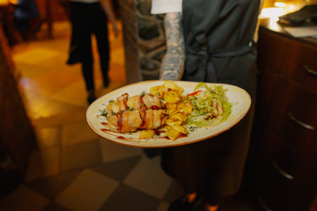 Delicious dishes on plates in the waiters handの写真素材