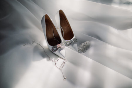White wedding shoes with jewelry on white fabricの写真素材