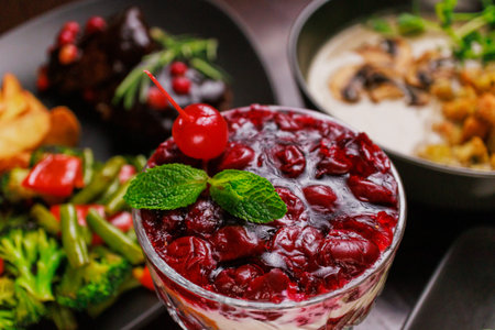 Dessert of pickled cherries with cream in a glass bowl