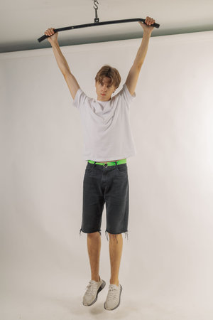 Handsome young guy in stylish clothes on white background in photo studio posing for camera