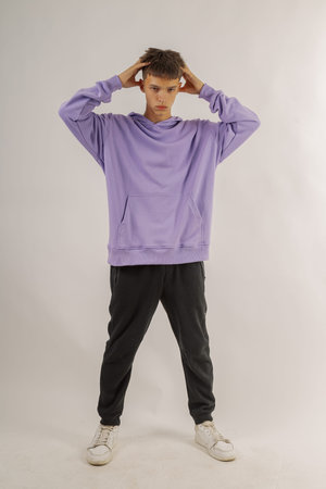 Handsome young guy in stylish clothes on white background in photo studio posing for camera