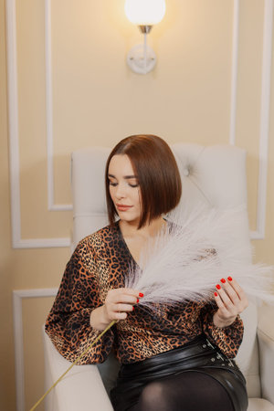 Beautiful portrait of a young girl sitting in a chair with feathers in her hands