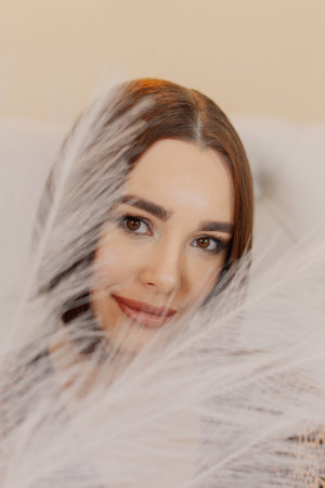 Beautiful portrait of a young girl sitting in a chair with feathers in her handsの写真素材