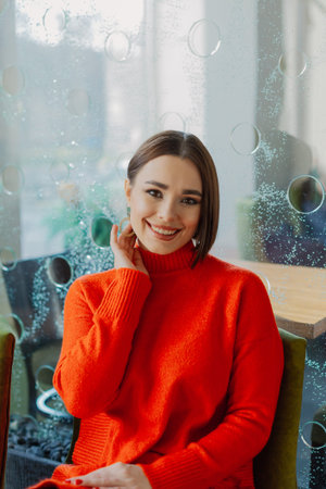 Beautiful young girl sits in a cafe at a table and poses