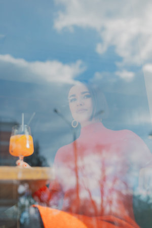 Beautiful young girl sits at a table in a cafe with a cocktail in her hands