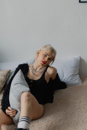 Beautiful woman posing for photographer on bed in photo studio