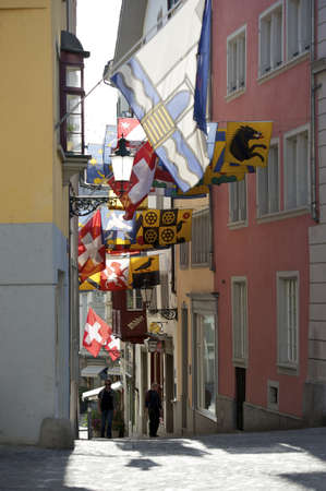 Zurich, Switzerland - April 10, 2011: Festive flagged old town alley with national flags and guild banners while the traditional spring festival called Sechselauten in Zurich, Switzerland.のeditorial素材