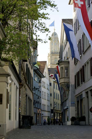 Zurich, Switzerland - April 10, 2011: Festive flagged old town alley with Zurich's landmark the Grossmunster in background.のeditorial素材