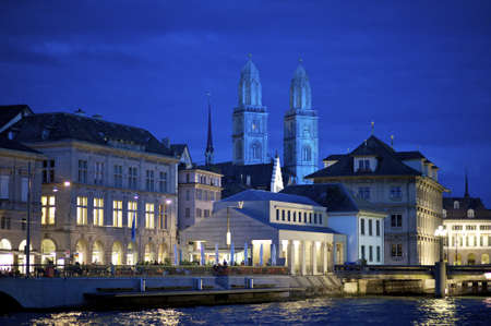 Zurich, Switzerland - June 20, 2011: Nightly scene of the old town of Zurich along the river Limmat with the towers of Grossmunster in the blue tinted background.のeditorial素材