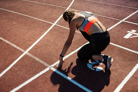 From above back view of teen athlete preparing for sprinting on track in starting positionの写真素材