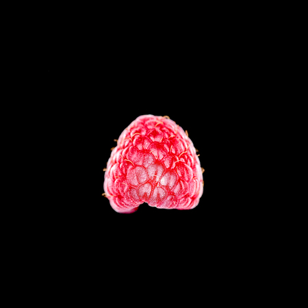Top view of single ripe raspberry on black background, copy space around