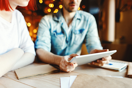 Young man and woman having informal business meeting in cafe. Colleagues discussing ideas and using tablet computerの写真素材
