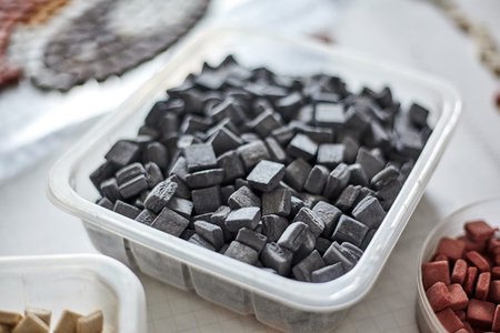 Closeup of plastic box filled with black-colored pieces of mosaicの写真素材