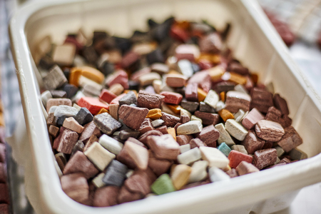 Closeup shot of small plastic container full of different colorful mosaic piecesの写真素材
