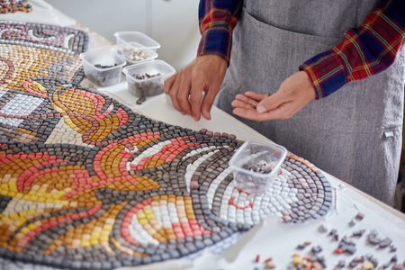 Faceless shot of man arranging mosaic pieces in colorful ornamental imageの写真素材
