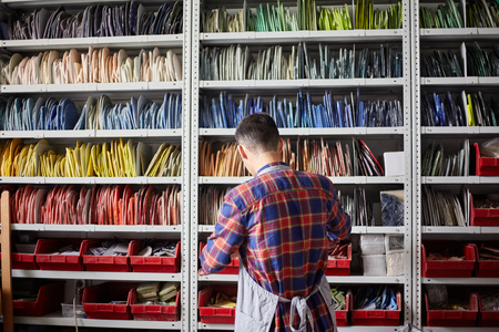 Back view of man standing near shelves with multicolored mosaic pieces in modern workshopの写真素材